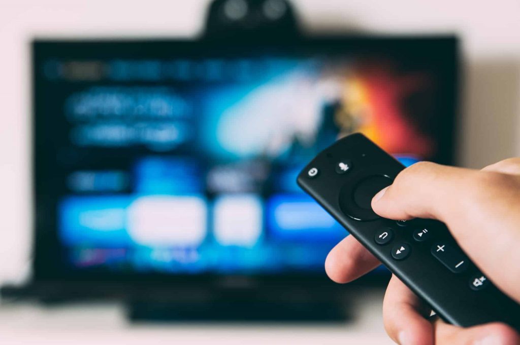 A person holding up A remote and streaming a show on tv